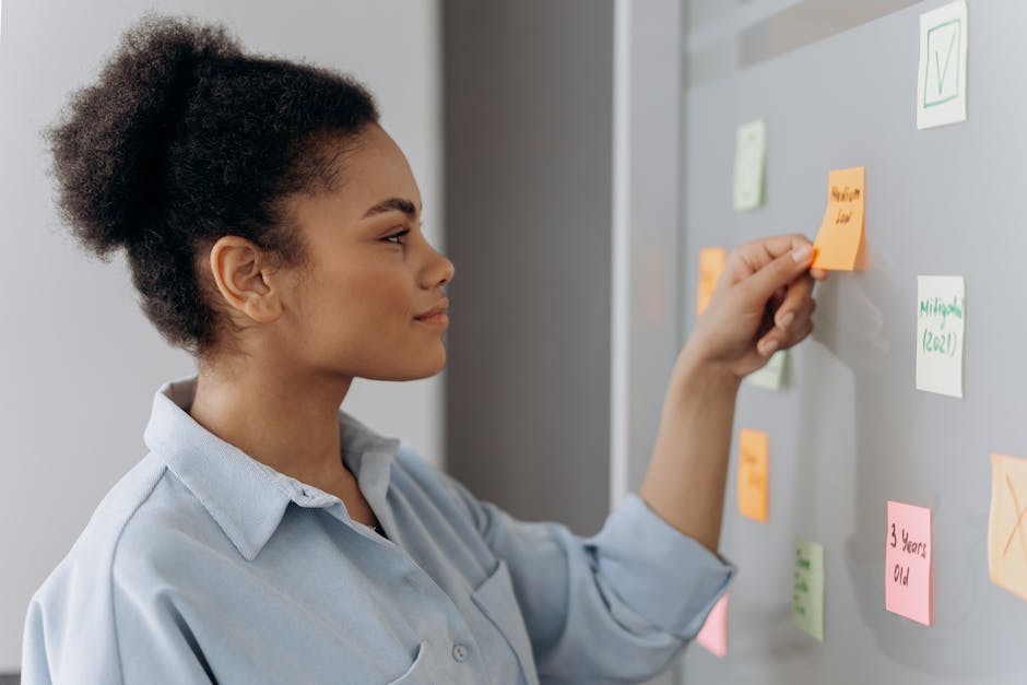 Side view of a woman placing sticky notes on a wall, indicating planning or brainstorming.